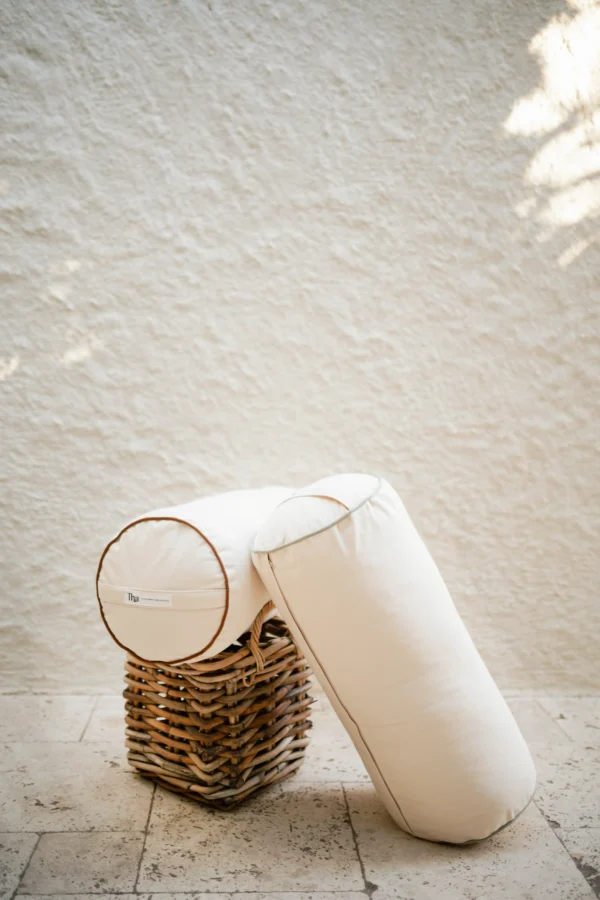 Kiremit ve mint tonunda keten–pamuk karışımı silindir yoga minderi, doğal dokusuyla detay çekimde görünüyor.